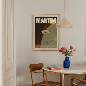 May include: A framed poster with the text "MARTINI" in bold, gold lettering. The poster features a martini glass with a cherry and olive, set against a red, black, and green background.
