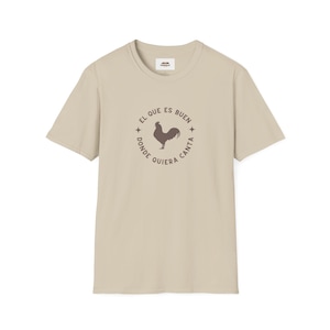 May include: A beige t-shirt with a brown rooster graphic and the text "El que es buen donde quiera canta" in a circle.