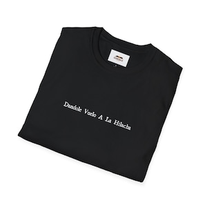 May include: Black t-shirt with white text that reads "Dandole Vuelo A La Hilacha".