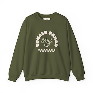 May include: A green sweatshirt with a white graphic print that says "Echale Ganas" with a hand gesture and a checkered pattern.