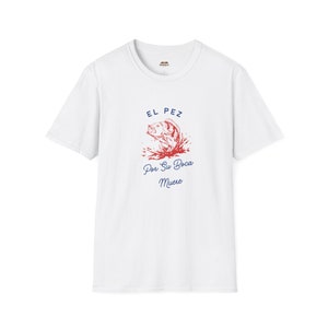May include: White t-shirt with a red and blue graphic of a fish jumping out of the water. The text "El Pez Por Su Boca Muere" is printed below the fish.