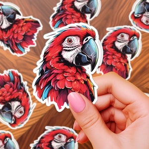 May include: A set of colorful red and blue macaw parrot stickers. The stickers are printed on white paper and feature a close-up of the parrot's head and neck.