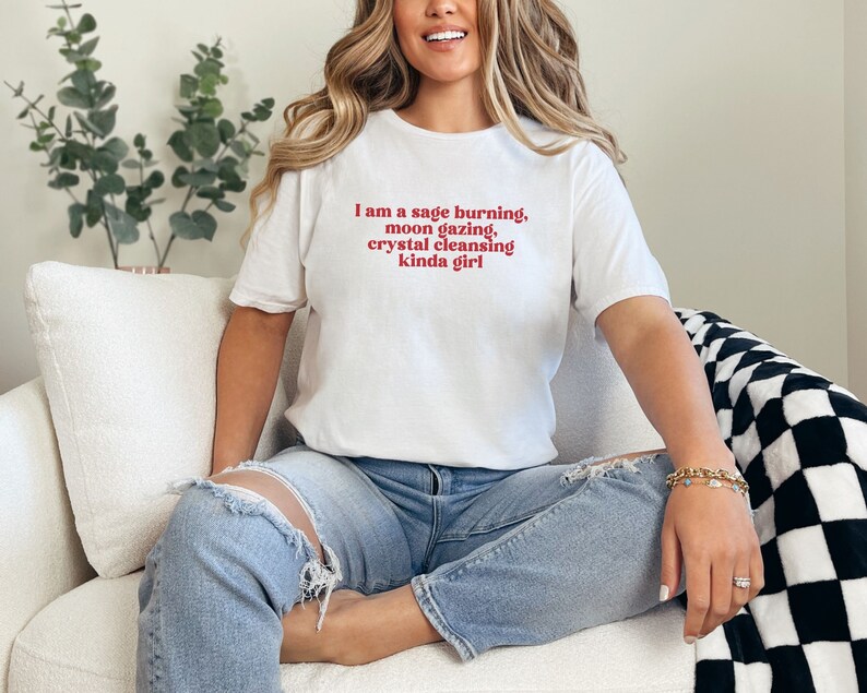 K&ouml;nnte beinhalten: Ein wei&szlig;es T-Shirt mit dem Text "I am a sage burning, moon gazing, crystal cleansing kinda girl" in Rot gedruckt.