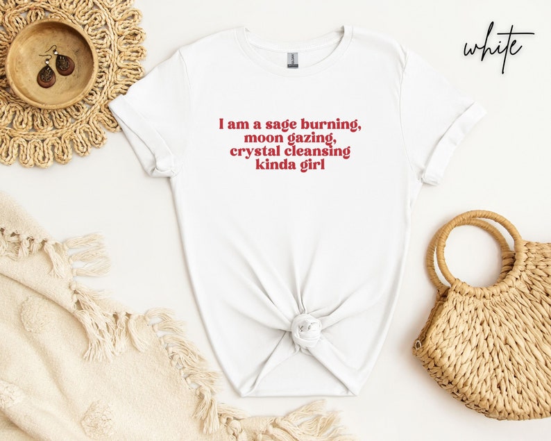 K&ouml;nnte beinhalten: Wei&szlig;es T-Shirt mit dem Text "I am a sage burning, moon gazing, crystal cleansing kinda girl" in Rot.