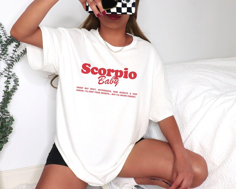 May include: White t-shirt with red text that reads "Scorpio Baby" and a description of the Scorpio personality.