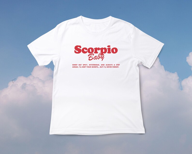 May include: White t-shirt with red text that reads "Scorpio Baby" and a short description about the zodiac sign.