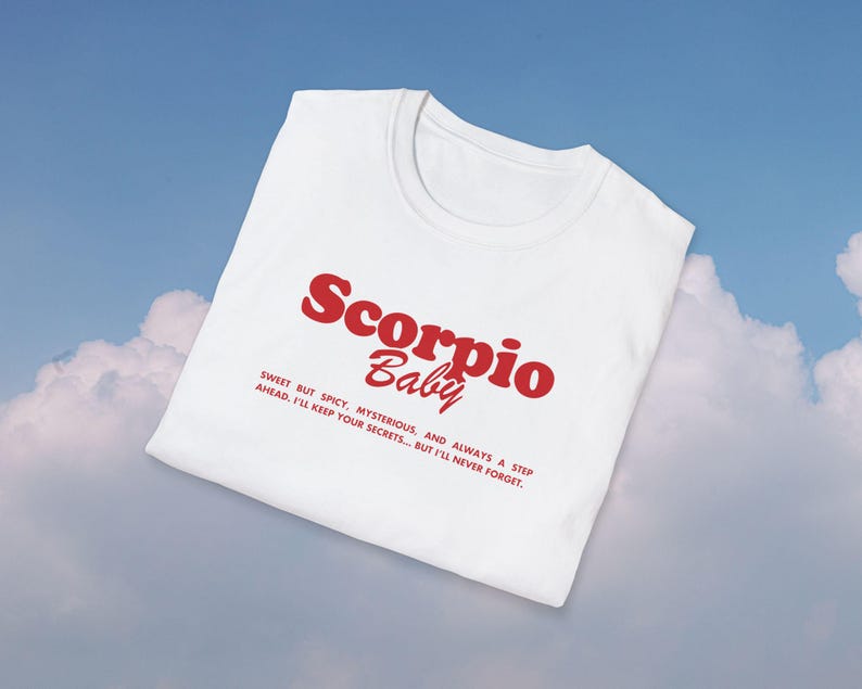 May include: White t-shirt with red text that reads "Scorpio Baby" and a description below: "Sweet but spicy, mysterious, and always a step ahead. I'll keep your secrets... but I'll never forget."