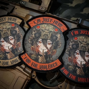 以下が含まれることがあります： 軍事装備を身につけたアニメ風キャラクターが描かれた刺繍パッチが3つ。パッチにはオレンジ色で「I'M JUST HERE FOR THE VIOLENCE」と書かれています。キャラクターは赤い目とオレンジ色の髪をしており、唇に指を当てています。