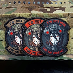 May include: Three embroidered patches with a military theme. Each patch features a stylized anime character with red eyes and a finger to the lips, wearing a helmet. Text on the patches reads "I'M JUST" and "FOR THE VIOLENCE".