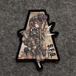 May include: A triangular patch featuring a cartoon image of a female soldier holding a rifle. The soldier is wearing a helmet, tactical gear, and a camouflage uniform. The patch has a brown and tan camouflage pattern and the text "S.F.G." in black.