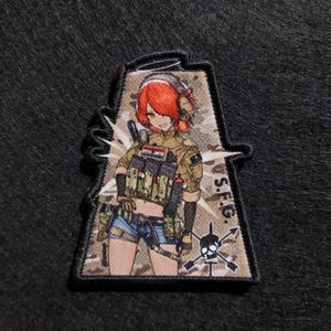 May include: A rectangular patch with an anime-style illustration of a female soldier with red hair, wearing a military uniform and headphones. The patch includes the text "S.F.G." and a skull and crossbones design.