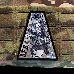 May include: A black, triangular patch with an anime-style character in military attire, holding a rifle. The character has white fur and wears a helmet. The text "S.F.G." is printed on the patch.