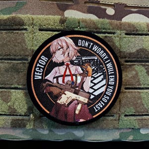 May include: A circular patch featuring an anime-style character and the word "VECTOR". The text "DON'T WORRY, I WILL END YOU SO FAST" is printed around the edge. The background is a camouflage pattern.