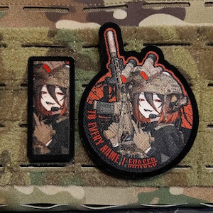 Op de afbeelding: Twee geborduurde patches met een anime-stijl karakter in militaire kleding. Eén is rechthoekig, de andere cirkelvormig, met de tekst "TO EVERY NAME I ANSWER". De patches zijn zwart met rode, bruine en beige accenten.