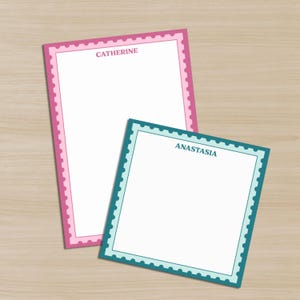 May include: Two personalized stationery notepads. One is rectangular with a pink border and the name "Catherine" printed at the top. The other is square with a teal border and the name "Anastasia". Both have a scalloped edge.