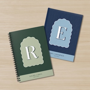 以下が含まれることがあります： パーソナライズされたノート2冊。1冊は濃い緑色で、文字「R」と「Rachel Garcia」の名前が入っています。もう1冊はネイビーブルーで、文字「E」と「Erica Thompson」の名前が入っています。どちらもユニークなスカラップデザインです。