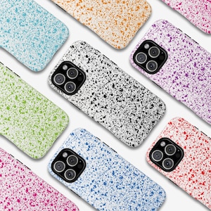 May include: A collection of colorful phone cases with a speckled paint design. The cases are in various colors, including blue, green, pink, purple, orange, and white, each with a contrasting splatter pattern. The cases have a glossy finish and a camera cutout.