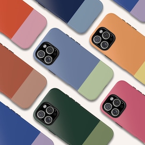 May include: Assortment of colorful phone cases with a two-tone design. Each case features a different color combination with a contrasting bottom half. The cases have a raised camera bump and a sleek, modern design.