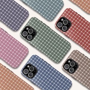 May include: A collection of phone cases in various colors, including purple, green, red, brown, and blue. Each case features a grid pattern in white, creating a checkered design. The cases are designed for a smartphone with a multi-lens camera.