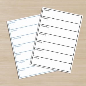 May include: Two weekly planner sheets on a light wood surface. One sheet has a blue border and text, the other has a black border. Both sheets are white with the days of the week printed at the top of each section: Monday, Tuesday, Wednesday, Thursday, Friday, Saturday, and Sunday.