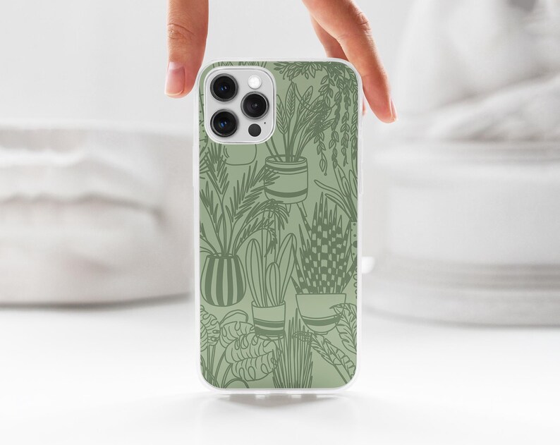 May include: A white phone case with a green outline design of potted plants. The phone case has a camera lens cutout.