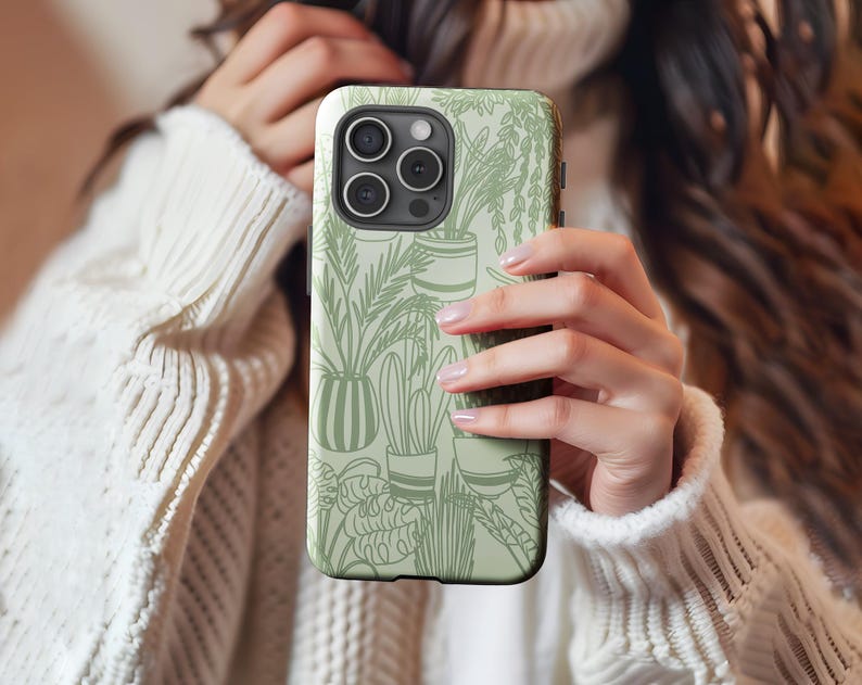 May include: A white phone case with a green and white design of potted plants. The case has a camera lens cutout and a black border.