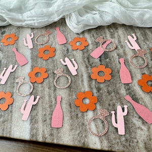 May include: Orange and pink confetti with cactus, flower, ring, and bottle shapes. The confetti is perfect for a bridal shower or bachelorette party.