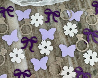 May include: Purple and gold confetti with butterflies, flowers, rings, and bows. The confetti is perfect for a wedding or bridal shower.