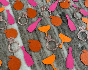 May include: Orange, pink, and gold confetti with images of champagne glasses, bottles, rings, and oranges.