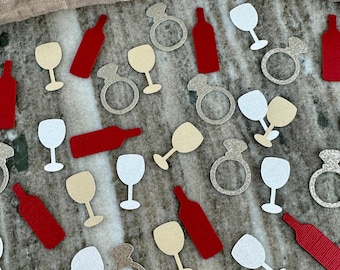 May include: Assortment of confetti featuring wine glasses, wine bottles, and engagement rings in red, white, and gold glitter.