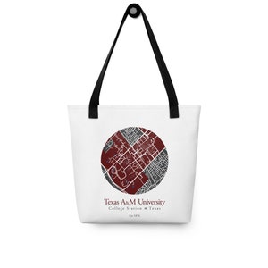 May include: White tote bag featuring a circular map design in maroon and gray, with the text "Texas A&M University, College Station, Texas, Est 1876." The bag has black handles and is suitable for carrying books, groceries, or other items.