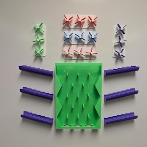 May include: A green plastic maze with purple plastic ramps and colorful plastic spinners. The maze has a series of holes and the spinners have different colored blades.