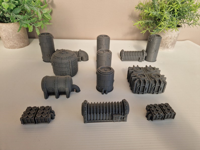 May include: A set of 10 gray 3D printed miniature buildings, resembling industrial structures with pipes, tanks, and vents. The buildings are made of a smooth, textured plastic.