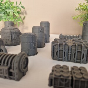 May include: A set of 3D printed gray industrial-style building models. The models are made of plastic and have a variety of shapes and sizes. They are perfect for use in tabletop games or as decorative pieces.