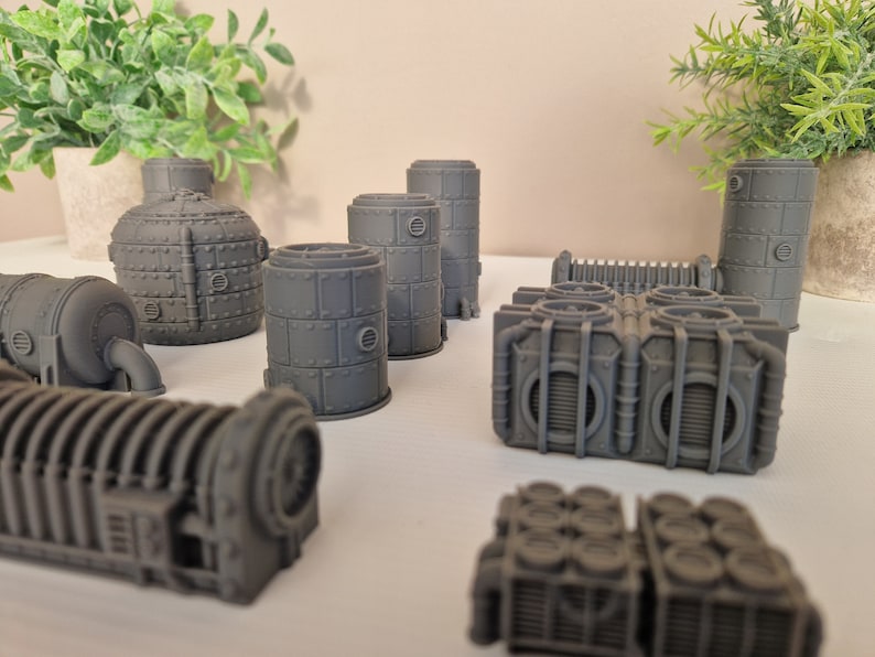 May include: A set of 3D printed gray industrial-style building models. The models are made of plastic and have a variety of shapes and sizes. They are perfect for use in tabletop games or as decorative pieces.