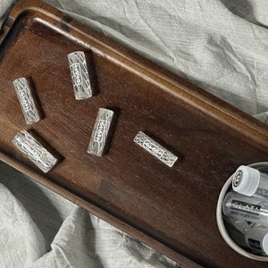 Può includere: Cinque fiale di vetro trasparente con una superficie testurizzata e la parola "GLATT" stampata su di esse. Le fiale sono disposte su un vassoio di legno.