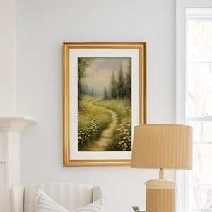 May include: A living room with a white and blue striped sofa, a white armchair with a striped pillow, a gold side table with books and a lamp, and a wicker coffee table with a white vase and flowers.