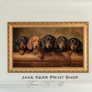 May include: A framed painting of five dachshund dogs peeking over a wooden ledge. The dogs are black and brown with a vintage style background. The painting is in a gold frame with the text "JANE KERR PRINT SHOP Frame Itv Art" below.
