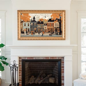 May include: A framed illustration of a quaint town street scene with colorful buildings, trees, and people walking. The illustration is in a gold frame and hangs above a fireplace.