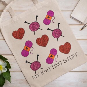 May include: A white canvas tote bag with the text "My Knitting Stuff" printed on it. The bag is decorated with a pattern of pink and red yarn balls, knitting needles, and hearts.