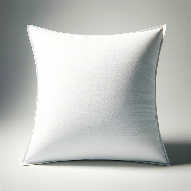May include: A square white pillow with a textured surface. The pillow has a white border and is set against a white background. The pillow is a neutral color and could be used for home decor.