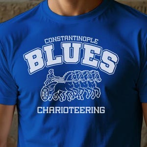 May include: Royal blue t-shirt with the words "Constantinople Blues" in white arched text above a graphic of a chariot race. The word "Charioteering" is printed below the graphic in white.