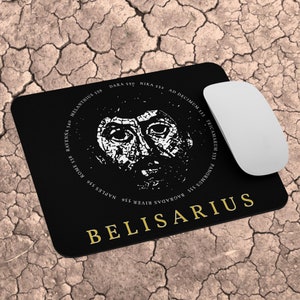 Puede incluir: Alfombrilla de ratón negra con una imagen blanca de la cara de un hombre y el texto "BELISARIUS" en letras doradas. La imagen está rodeada por un círculo de texto en letras doradas, que incluye fechas y lugares.