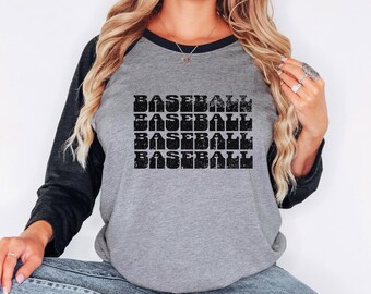 May include: A gray and black baseball raglan t-shirt with the word "BASEBALL" repeated four times in a vintage style font.