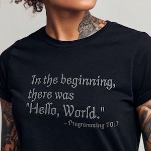 May include: A black t-shirt with a white graphic print that reads "In the beginning, there was "Hello, World." -Programming 10:1"