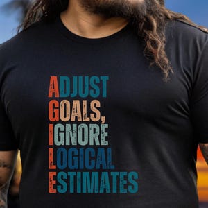 Puede incluir: Una camiseta negra con un gráfico de estilo vintage que dice "AGILE: ADJUST GOALS, IGNORE LOGICAL ESTIMATES".