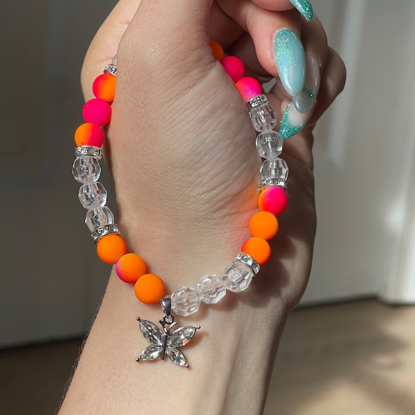 Crystal and Pink & orange fluorescent beads accented with silver diamond encrusted spacers and butterfly charm handcrafted stretch bracelet