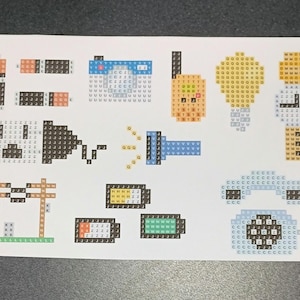 May include: A sheet of paper with pixel art designs of various objects, including a camera, a light bulb, a flashlight, a battery, a telephone, and a power line.
