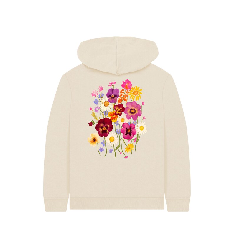 May include: Cream-colored hoodie with a floral design on the back. The floral arrangement features a variety of colorful flowers, including purple pansies, pink daisies, and yellow sunflowers. The hoodie has a hood and long sleeves.