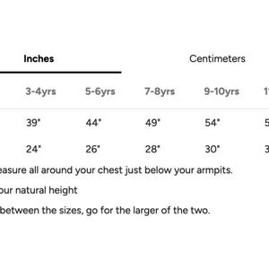 May include: A white chart with size measurements in inches and centimeters for children's clothing. The chart includes height and chest measurements for ages 3-12 years old. Text at the bottom advises to choose the larger size if between sizes.